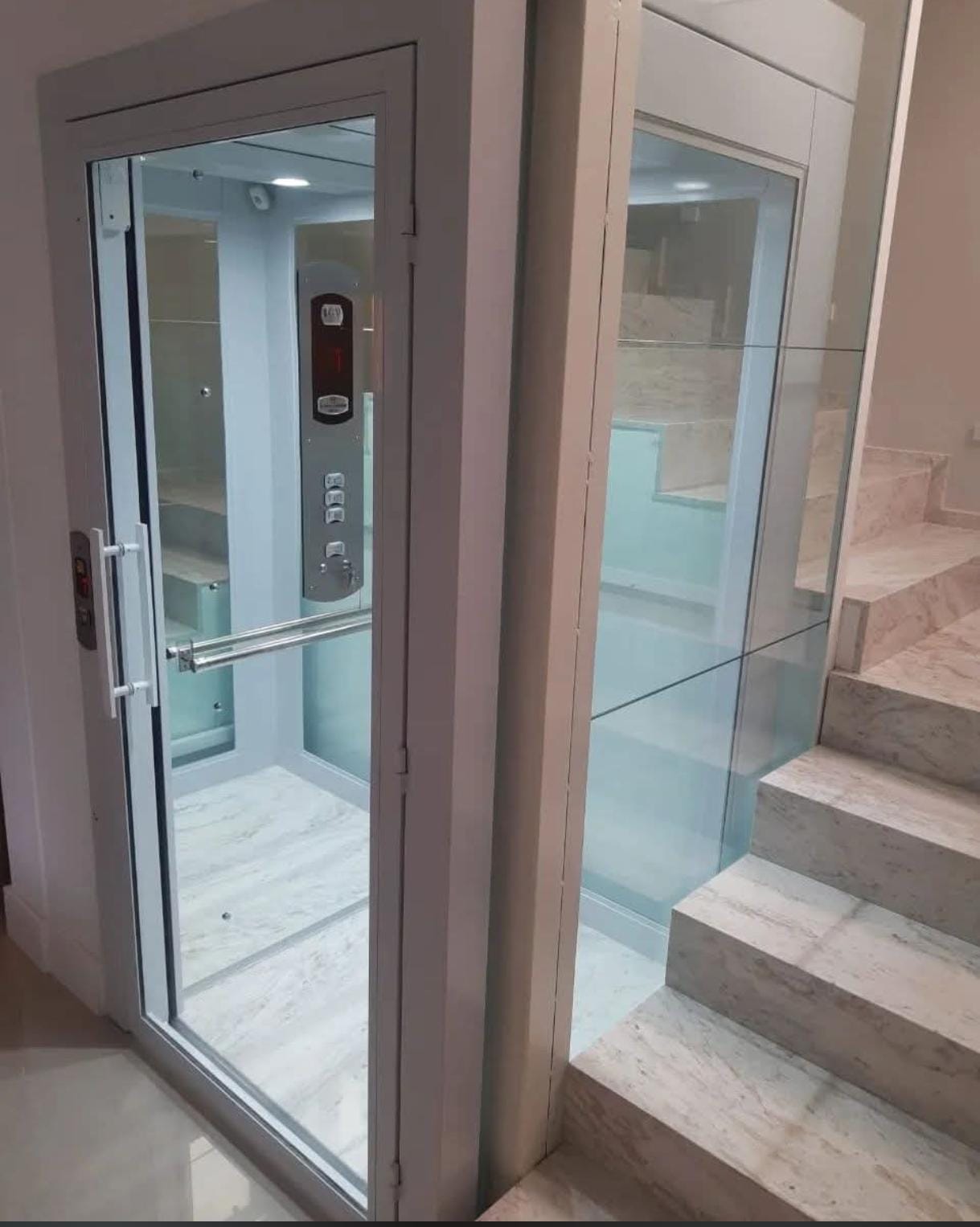 Elevador residencial em vidro instalado ao lado de escada interna